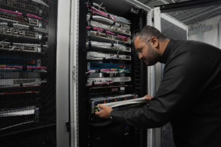 A BAE Systems engineer examines a rack of servers