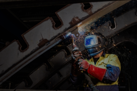 A welder in a helmet holds a torch, showcasing the manufacturing process at BAE Systems.
