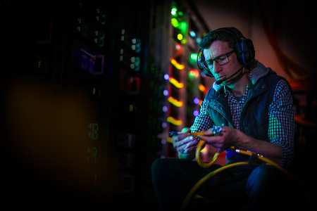 BAE Systems Australia engineer wearing headphones in a dimly lit workspace.