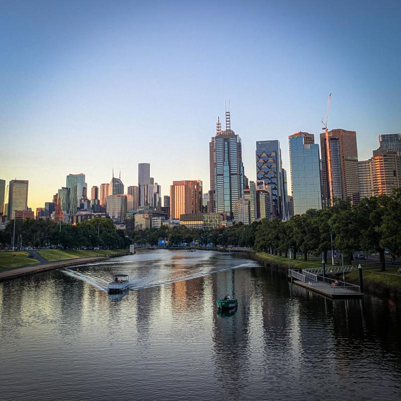 A scenic view of a river in Melbourne with a boat gently floating on the water.